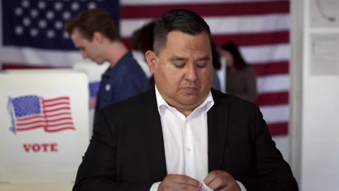 Hispanic man puts on "I Voted" sticker at polling station HD Video stock 137754949