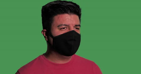 Hispanic man puts on mask in front of green screen. Stock Footage 139102968