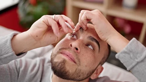 Hispanic man putting eye drops in at home Stock Footage 247384298