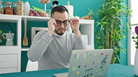 Hispanic man putting glasses to use laptop at dinning room Stock Footage 246143254