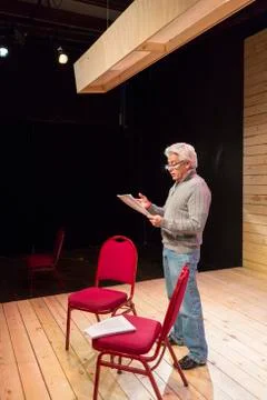 Hispanic man reading script on theater stage Stock Photos