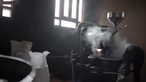 An Hispanic man is releasing coffee beans from a roaster machine with steam Stock Footage 219592454