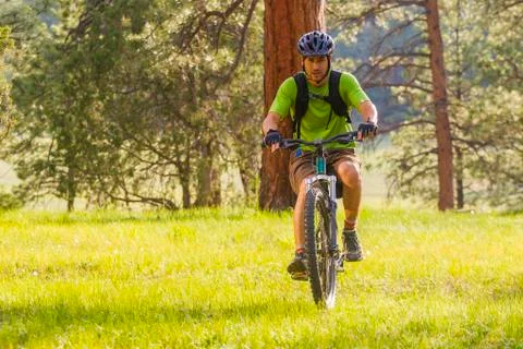 Hispanic man riding mountain bike in meadow Stock Photos