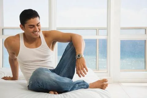 Hispanic man sitting on bed Foto stock