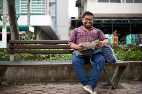 Hispanic man sitting on bench reading brochure Fotos de archivo
