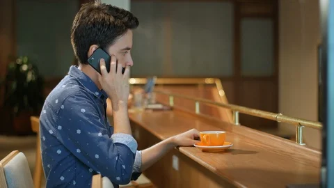Hispanic man sitting in coffee shop talking on cell phone and drinking coffee Stockbeeldmateriaal 101683098