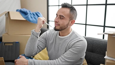 Hispanic man sitting on the sofa thinking about an idea at new home Video stock 247384309