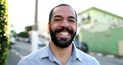 Hispanic man smiling at camera standing outside in street. South American per Stock Footage 144389584