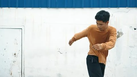 Hispanic man stretch arms and dance street dancing in front of wall. Endeavor. Stock Photos