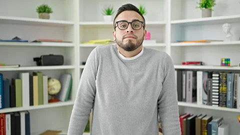 Hispanic man student standing with i dont know expression at library universi Stock Footage 246143240