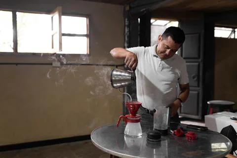 An Hispanic man is taking a break preparing fresh filtered coffee Stock-Fotos
