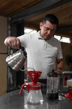 An Hispanic man is taking a break preparing fresh filtered coffee Stock-Fotos