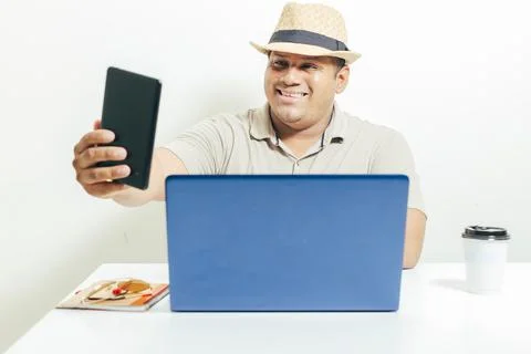 Hispanic man taking a self-portrait with his cell phone while working on his  Stock Photos