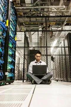 Hispanic man technician doing diagnostic tests on computer servers in a large Stock Photos