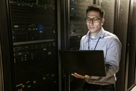 Hispanic man technician doing diagnostic tests on computer servers in a large Stock Photos