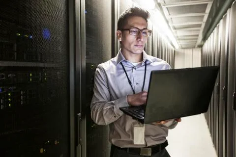 Hispanic man technician doing diagnostic tests on computer servers in a large Stock Photos
