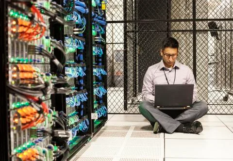 Hispanic man technician doing diagnostic tests on computer servers in a large Stock Photos
