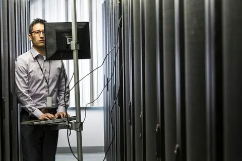 Hispanic man technician doing diagnostic tests on computer servers in a large Stock Photos