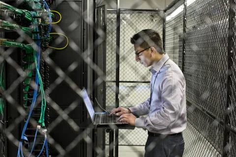Hispanic man technician doing diagnostic tests on computer servers in a large Stock Photos