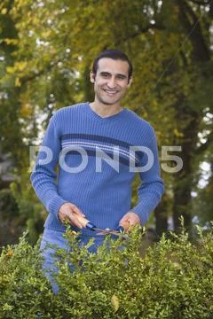 Hispanic man trimming hedges Stock Photos