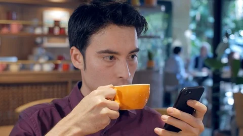Hispanic man using his smartphone cell phone, and drinking coffee Vídeo Stock 101707930
