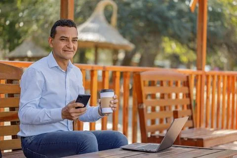 Hispanic man using a laptop while drinking coffee in a bar. Stockfoto's