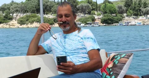 Hispanic man using smartphone during vacation on yacht 3 Stock Footage 135713032
