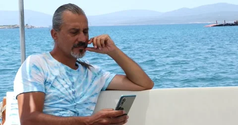 Hispanic man using smartphone during vacation on yacht Stock Footage 137392814