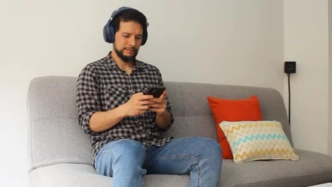 A hispanic man using a wireless headset texting in his smartphone Stock Footage 340583391