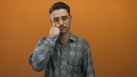 Hispanic man wearing patterned shirt and glasses resting thoughtfully on hi.. Stock Footage 312338520