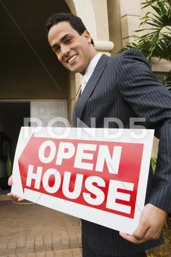 Hispanic Real Estate Agent Holding Open House Sign