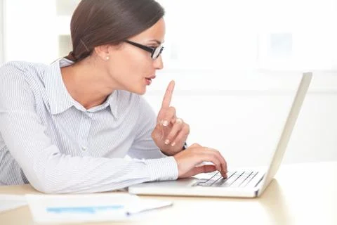Hispanic receptionist with glasses using her laptop while shushing Stock Photos