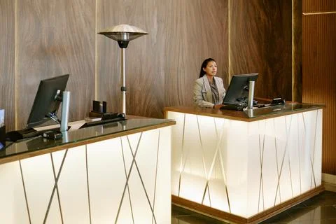 Hispanic Receptionist Woman Working on Computer in Hotel Lobby Stock Photos
