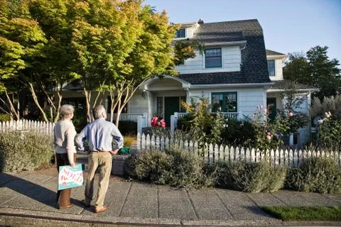 HIspanic seniors in front of their newly puchased remodeled older style home. Stock Photos