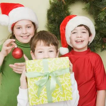 Hispanic siblings in Santa Claus hats with gift Stock Photos