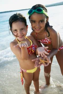 Hispanic sisters holding starfish Stock Photos