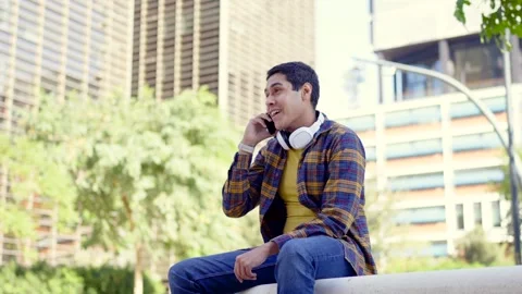 Hispanic student talking to the mobile happily Stock Footage 258326221