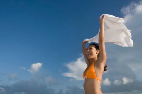 Hispanic woman in bikini holding skirt in wind Stock Photos