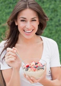 Hispanic woman eating cereal with fresh fruit Stock Photos