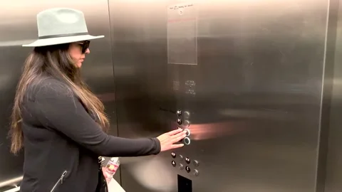 Hispanic woman in an elevator pushing a floor button Stock Footage 233587311