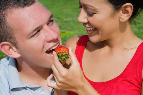 Hispanic woman feeding strawberry to boyfriend Stock Photos