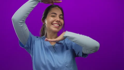 Hispanic woman frames head with hands and smiles in purple studio, creating.. Video stock 313081188