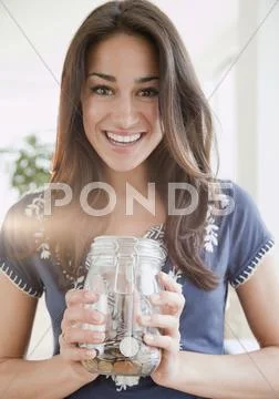 Hispanic woman holding jar of coins Stock Photos