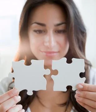 Hispanic woman holding two puzzle pieces Stock Photos