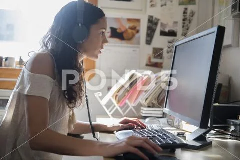 Hispanic woman listening to computer with headphones Stock Photos