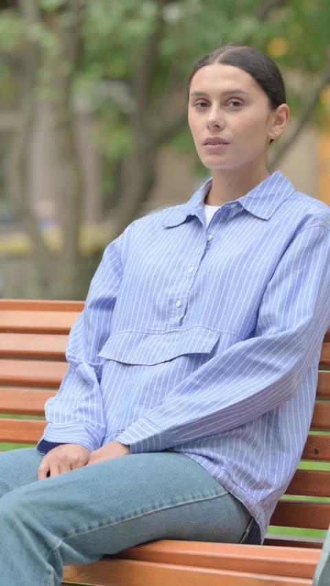 Hispanic Woman Looking at Camera while Sititng Outdoor, vertical Stockbeeldmateriaal 321121674