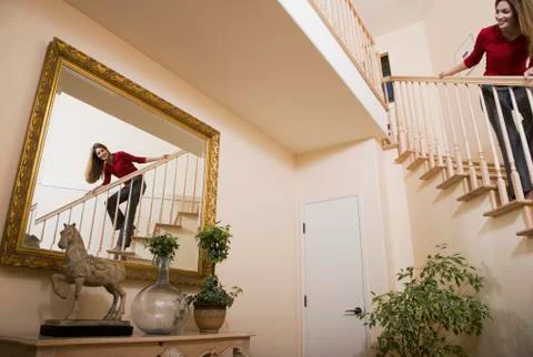 Hispanic woman looking in mirror from stairs Stock Photos