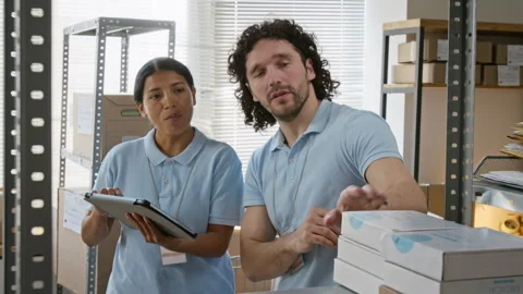 Hispanic Woman with Man Checking Inventory on Tablet in Warehouse Stock Footage 346057946
