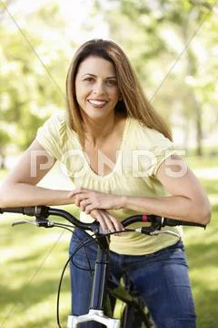 Hispanic woman in park with bike Stock Photos