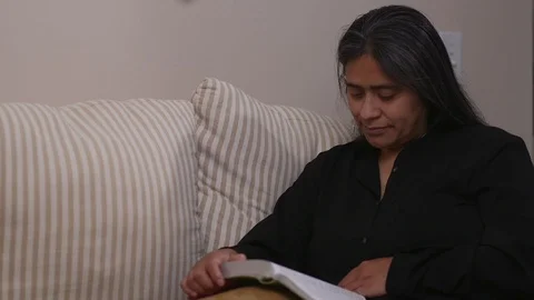 Hispanic Woman Studying Bible While Sitting on Sofa Stock Footage 110771728